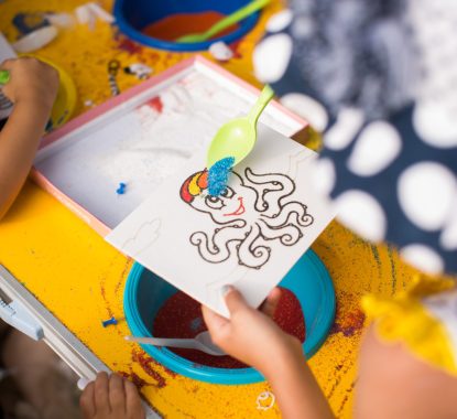 A child draws with colored sand picture. Cartoon characters.
